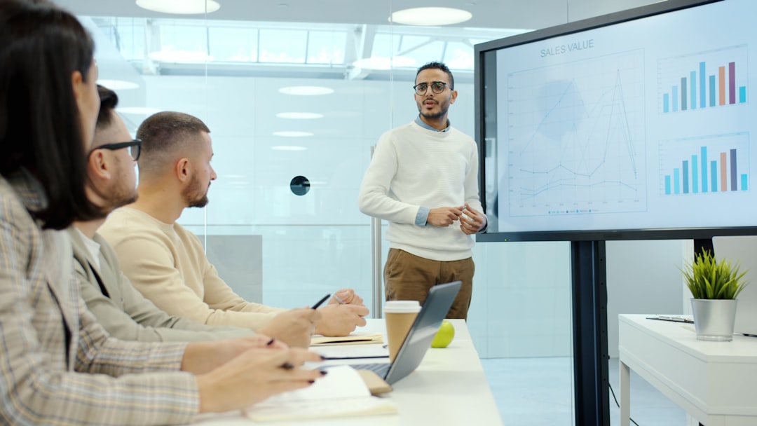 Arabian man employee is giving presentation to group of colleagues in conference room speaking and showing infographics on digital whiteboard.
