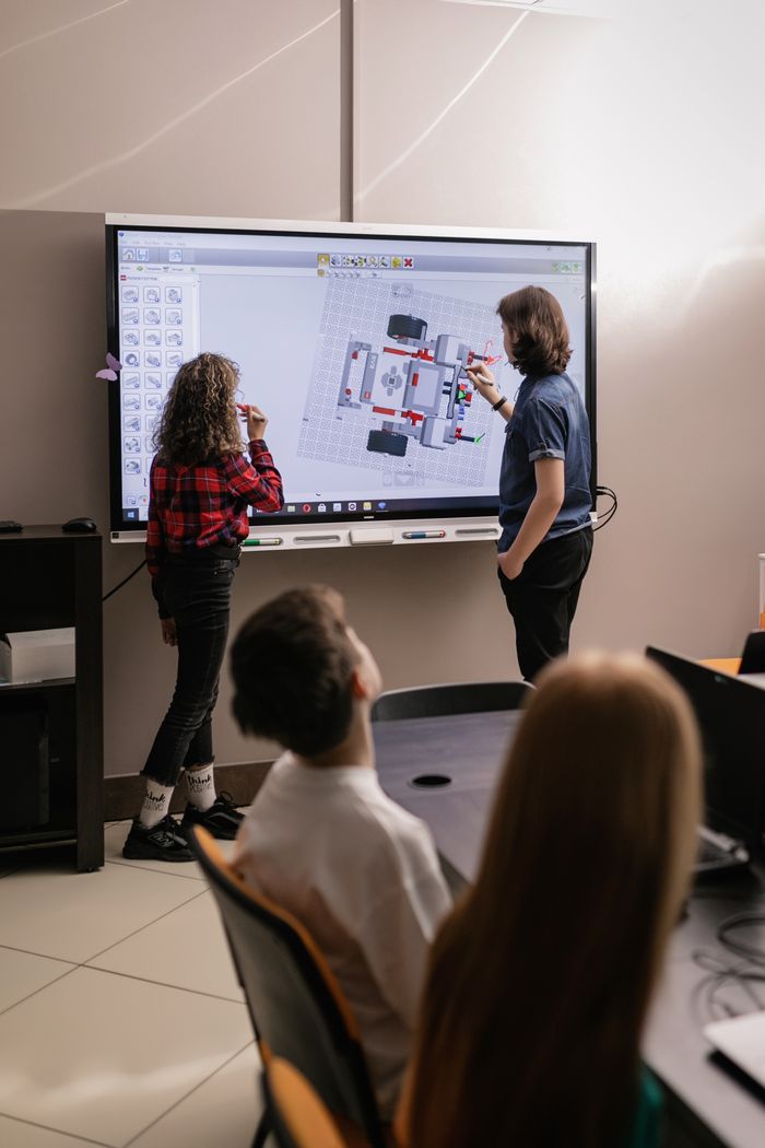 Teens engaged in robotics teamwork in a modern classroom setting.
